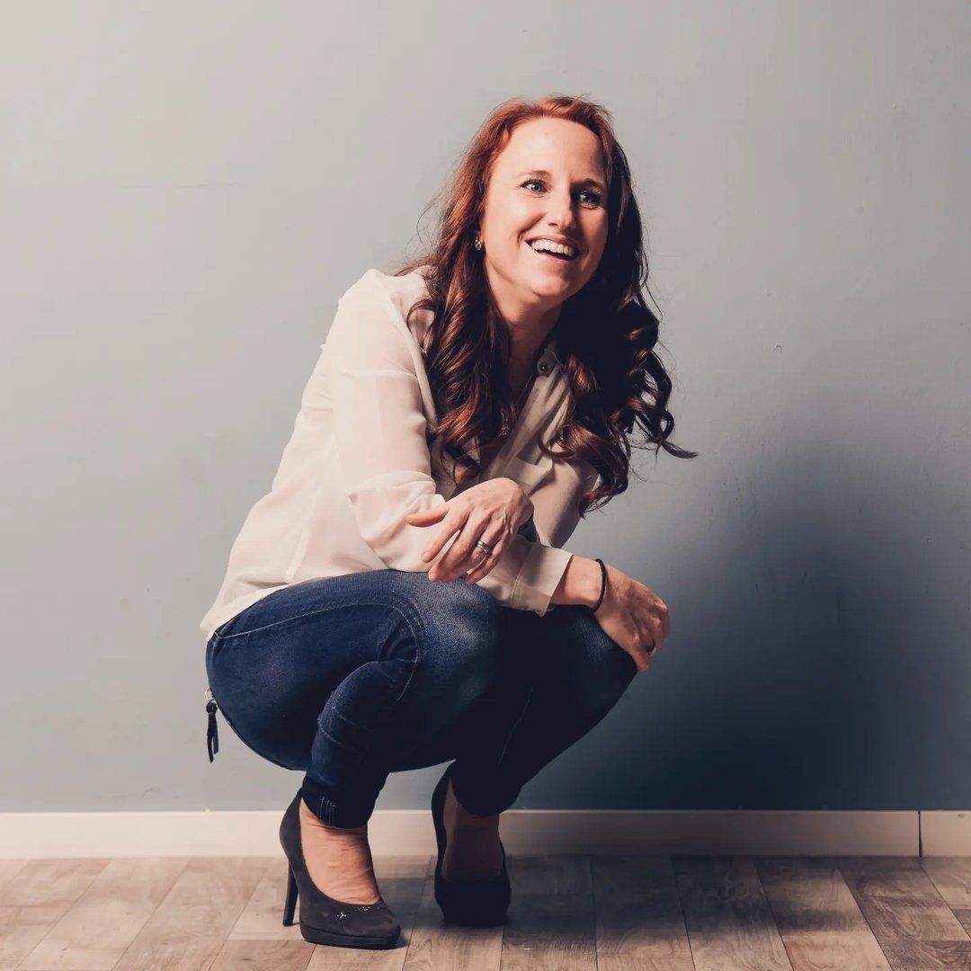 Angelika Grabner, sitzend und lachend vor einer hellen Wand